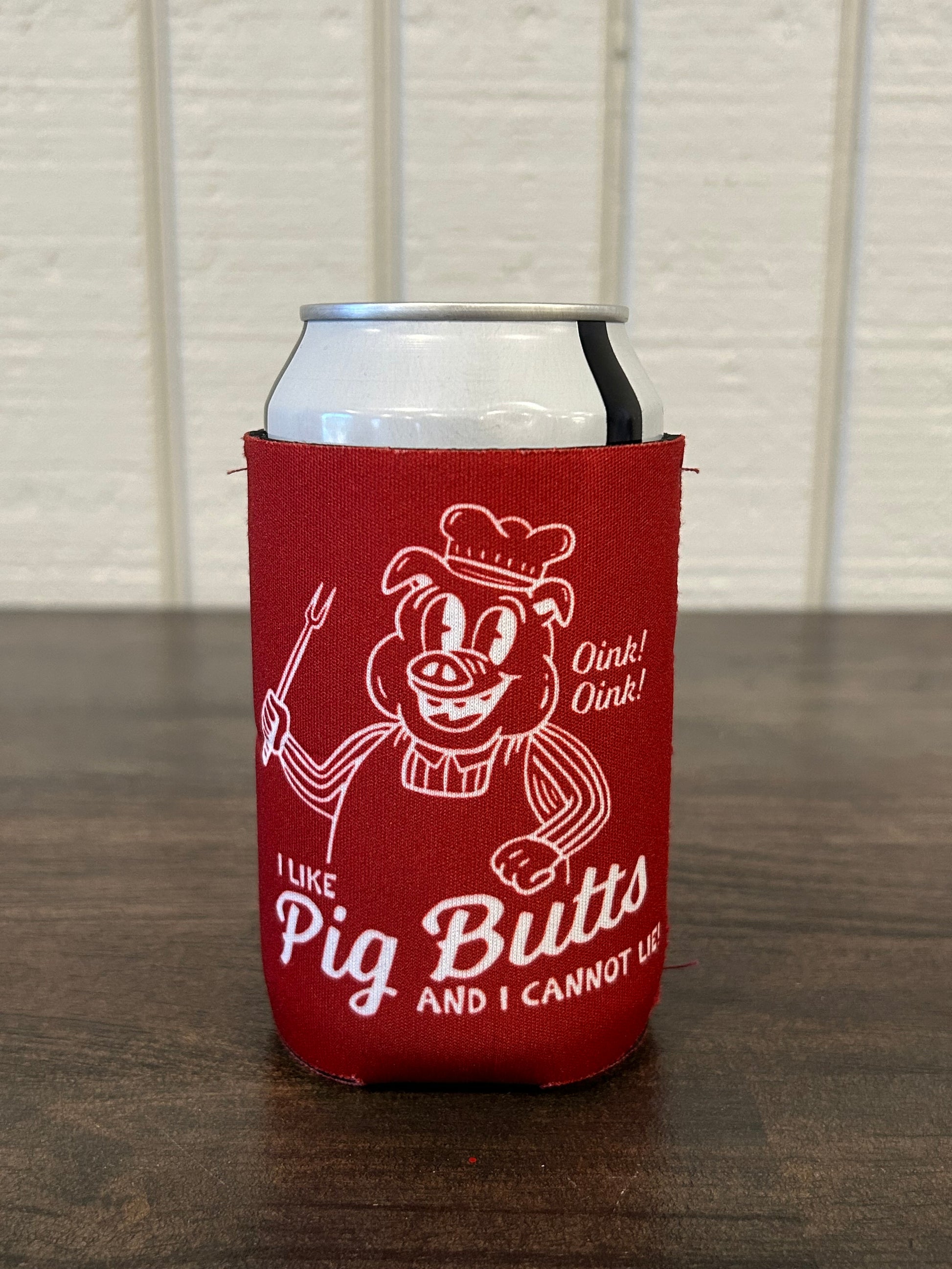 Red can cooler with white graphic of pig cooking barbecue and white text saying I Like Pig Butts And I Cannot Lie